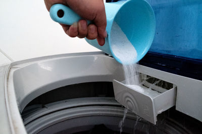 Cropped hand pouring detergent in washing machine