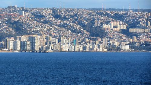 Aerial view of city by sea against sky