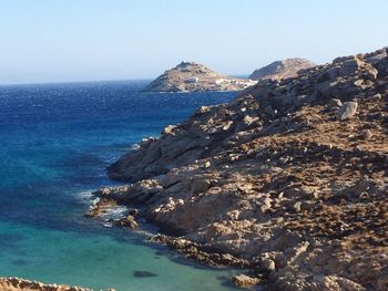 Scenic view of mountains at sea shore against clear sky