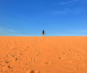Man standing on sand in desert against sky