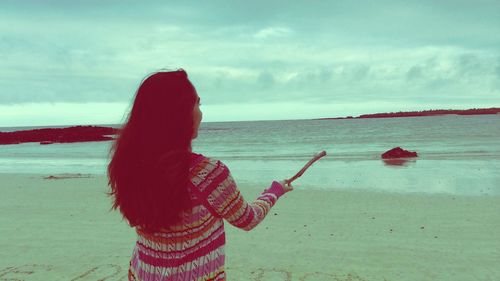 Midsection of woman standing on beach against sky
