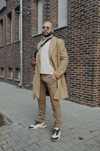 Full length of young man standing against wall