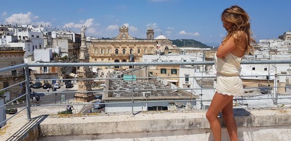 Side view of woman standing on building terrace during sunny day