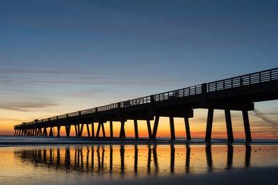 Low angle view of silhouette pier at sea against sky during sunset 