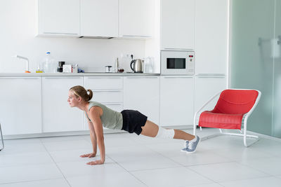 Fitness, home and diet concept. smiling young woman stretching at home, in the kitchen