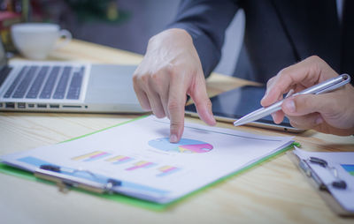 Midsection of businessman discussing graphs with coworker in office