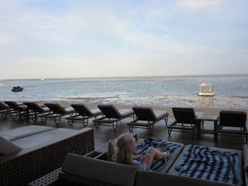 Lounge chairs by swimming pool at beach against sky