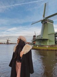 Woman looking away while standing against traditional windmill