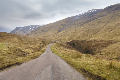 Road leading towards mountains against sky