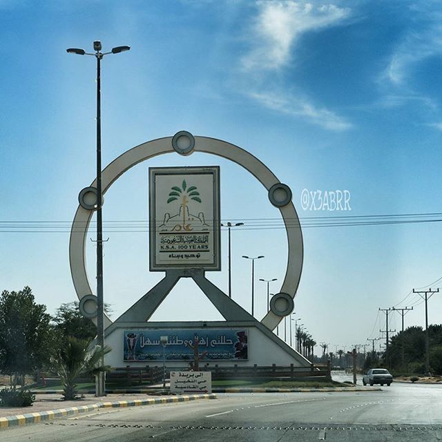road sign, communication, text, transportation, road, western script, sign, information sign, guidance, street light, arrow symbol, street, sky, road marking, human representation, blue, information, low angle view, warning sign, directional sign