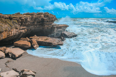 Scenic view of rocks on beach against sky