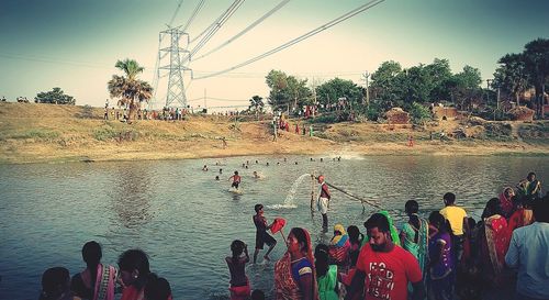 People by river against sky