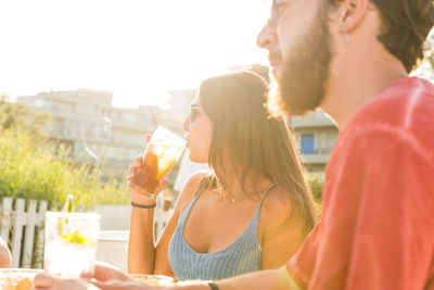 Woman drinking while sitting at restaurant outdoors