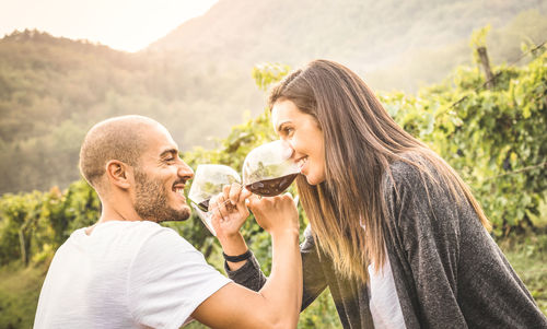 Boyfriend and girlfriend enjoying wine in vineyard