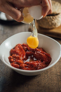 Cropped hand breaking egg in bowl