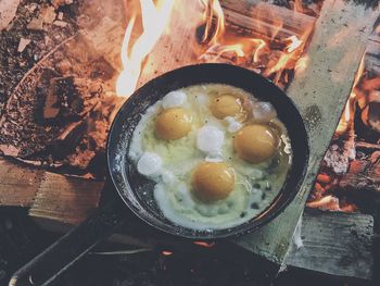 High angle view of eggs in cooking pan over burning wood