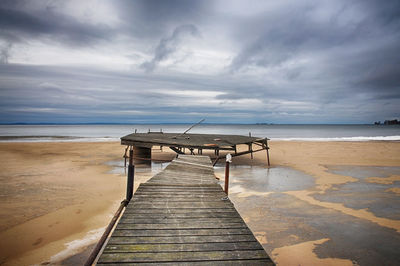 Empty pier on beach against sky