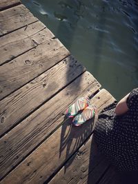 Midsection of woman sitting on wooden pier by lake