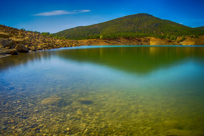 Scenic view of lake and mountains against blue sky