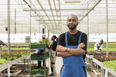 Portrait of young man standing in greenhouse
