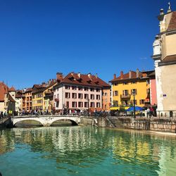 Bridge over canal by buildings against blue sky