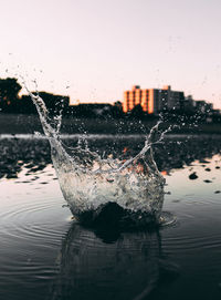 Close-up of water splashing against sky at sunset