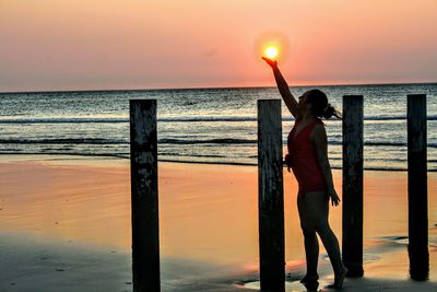 Woman standing at beach during sunset