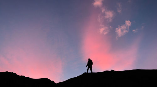 Silhouette of a man standing on mountain against sky during sunset