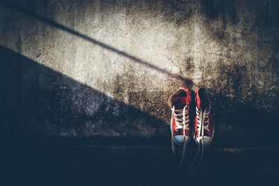 High angle view of person sitting on footpath against wall