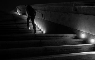 Rear view of man walking on illuminated steps