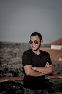 Young man wearing sunglasses standing against sky