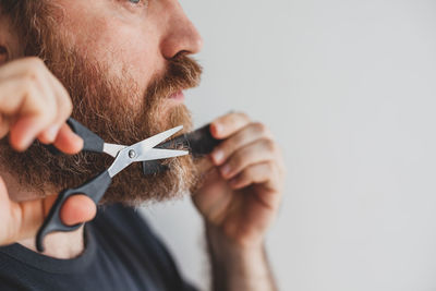 Man trimming beard with scissors at home