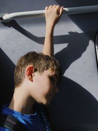 Side view of boy holding handle while standing in train