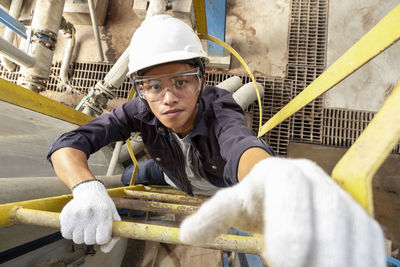 High angle portrait of man on ladder working in industry