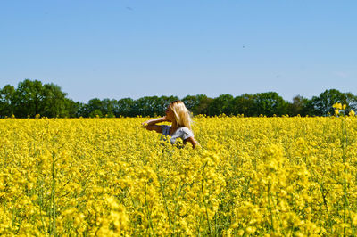 Young woman standing amidst field against clear sky