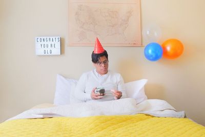 Midsection of man holding balloons on bed at home