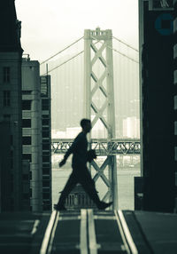 Silhouette man on bridge against sky in city