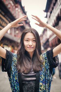 Portrait of smiling young woman with arms raised