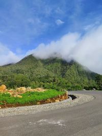 Scenic view of road by mountains against sky