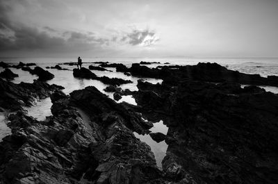 Rocks on beach against sky at dusk