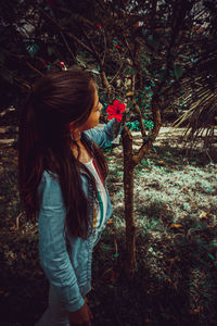 Girl holding flower on tree in forest