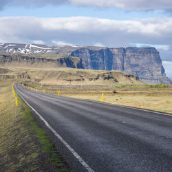 Road leading towards mountains against sky