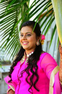 Smiling young woman standing below palm leaves