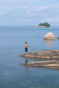 Man standing on rock in sea