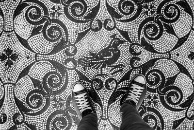 Low section of man standing on tiled floor pattern