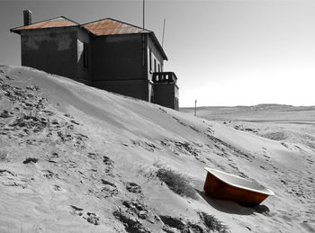 House on snow covered land against sky