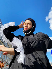 Low angle view of woman standing against sky