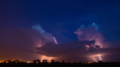 Lightening over silhouette landscape at night