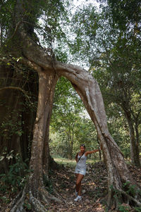 Woman standing by tree in forest