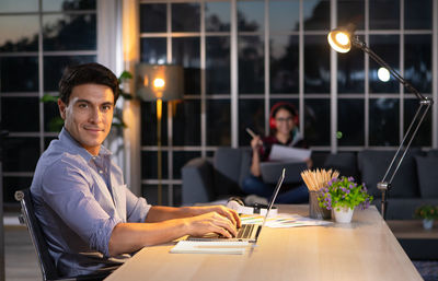 Portrait of young man using mobile phone at table